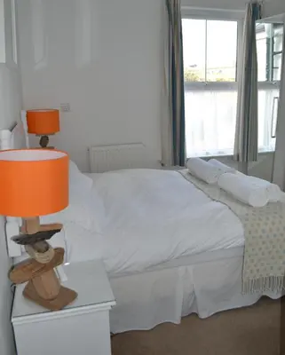 a bedroom with a bed with a lamp on a night stand at Tregony Guest House in St Ives