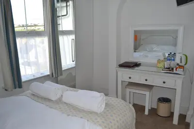 a bedroom with a bed and a desk with a mirror at Tregony Guest House in St Ives