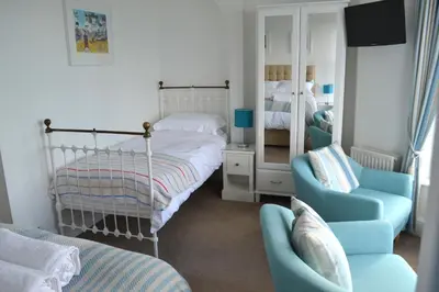 a bedroom with a bed and a chair and a mirror at Tregony Guest House in St Ives