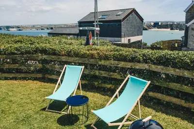 two chairs sitting on the grass next to a fence at Harvest Moon in Newquay