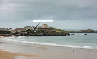 a view of a beach with a sign on a hill at Harvest Moon in Newquay