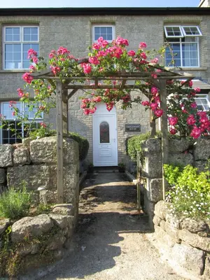 an archway with pink flowers on it in front of a building at Treganoon House, Lanlivery in Bodmin
