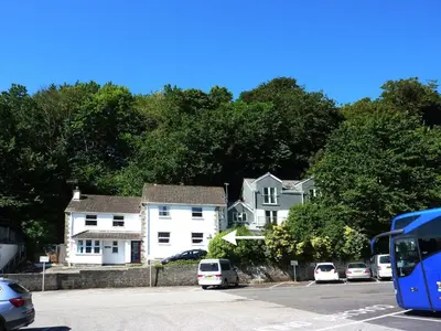 a blue bus parked in a parking lot with houses at Stones Throw in Saint Mawes