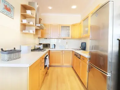 a kitchen with wooden cabinets and a stainless steel refrigerator at Seashore House in Newquay