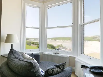 a living room with a chair and three windows at Seashore House in Newquay