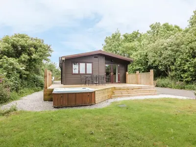 a small cabin with a deck and a hot tub at Oak Lodge in Falmouth