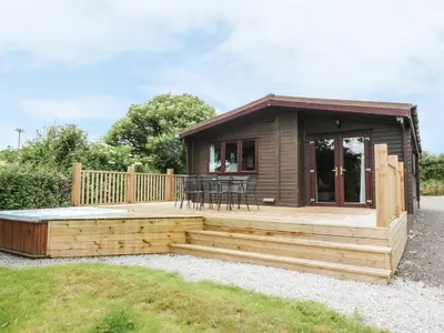 a small cabin with a deck and a table at Oak Lodge in Falmouth