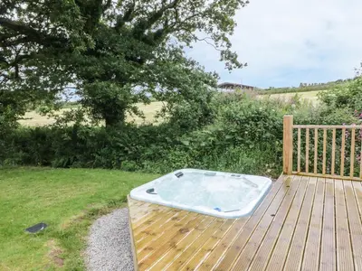 a hot tub sitting on top of a wooden deck at Oak Lodge in Falmouth