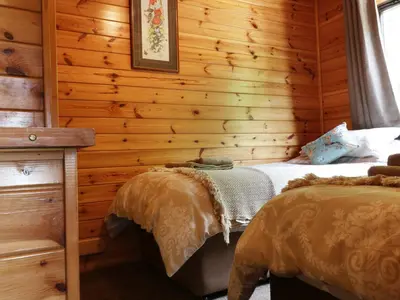 a bedroom with wooden walls and two beds in it at Oak Lodge in Falmouth