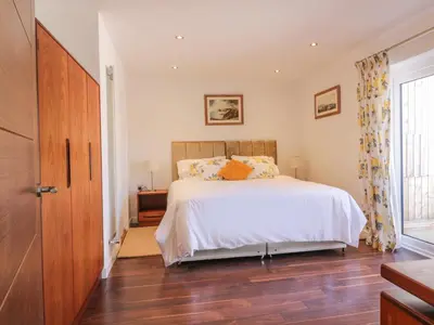 a bedroom with a bed and a wooden floor at Chy Lagen Hos in Newquay