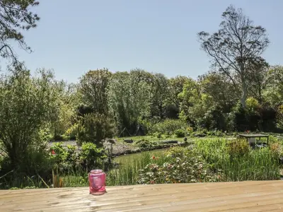 a pink cup sitting on a wooden table in a garden at Chy Lagen Hos in Newquay