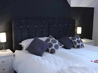 a bedroom with a white bed with blue pillows at The Red House Guest House in Falmouth