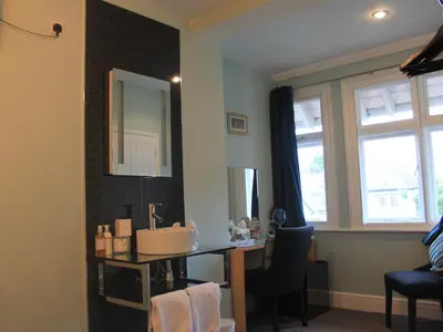 a bathroom with a sink and a desk with a mirror at The Red House Guest House in Falmouth