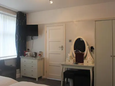 a bedroom with a bed and a desk and a mirror at The Red House Guest House in Falmouth