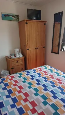 a bedroom with a colorful quilt on a bed at Fairways Guest House in Newquay