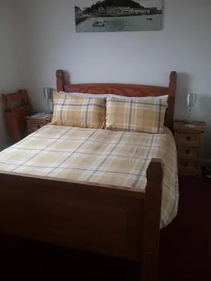 a bed with a plaid blanket and two pillows at Fairways Guest House in Newquay