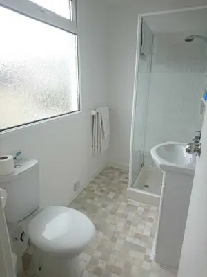 a white bathroom with a toilet and a sink at Fairways Guest House in Newquay