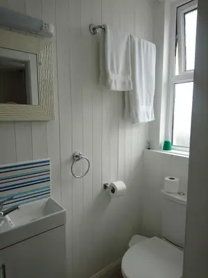 a white bathroom with a toilet and a sink at Fairways Guest House in Newquay