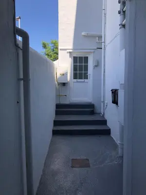 a stairway leading to a white building with a door at The Cottage in Redruth