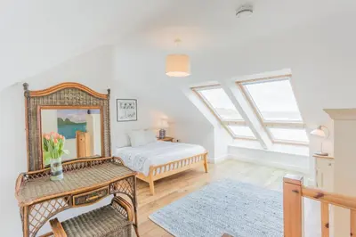 a bedroom with a bed and a table with a mirror at Tolcarne Beach Apartments in Newquay