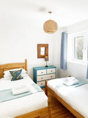 a bedroom with two beds and a blue dresser at Tolcarne Beach Apartments in Newquay
