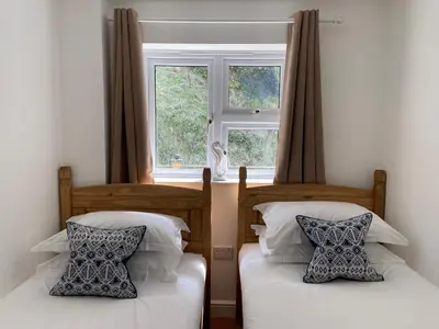 two beds in a room with a window at Tolcarne Beach Apartments in Newquay