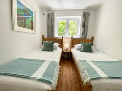 two twin beds in a room with a window at Tolcarne Beach Apartments in Newquay