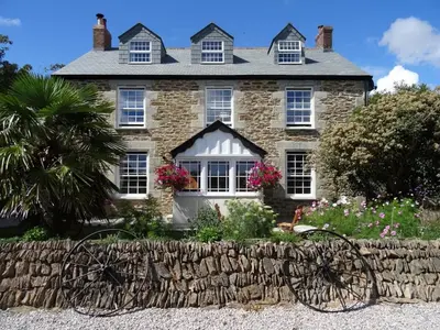 a large stone house with a stone fence in front of it at Pengelly Farmhouse B&B in Truro