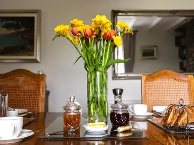 a vase filled with yellow and red flowers on a table at Pengelly Farmhouse B&B in Truro