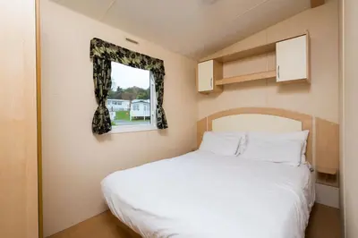 a bedroom with a white bed and a window at Newperran Holiday Resort in Newquay