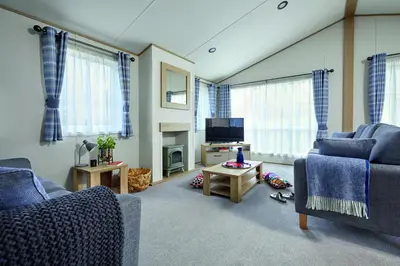 a living room with two blue couches and a tv at Newperran Holiday Resort in Newquay