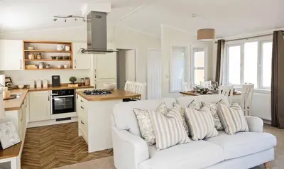 a living room with a white couch and a kitchen at Newperran Holiday Resort in Newquay