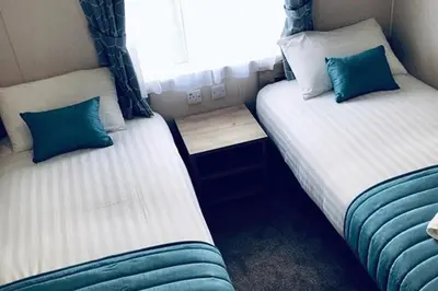 two beds in a small room with blue and white at Newperran Holiday Resort in Newquay