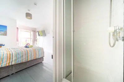 a bedroom with a bed and a walk in shower at Palace Guesthouse in Newquay