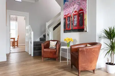 a living room with two chairs and a staircase at Gyllyngvase House in Falmouth