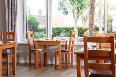 a dining room with a table and chairs and a window at Gyllyngvase House in Falmouth