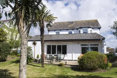 a white house with palm trees in the yard at Gyllyngvase House in Falmouth
