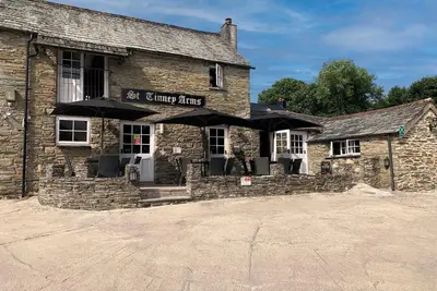 a stone building with umbrellas in front of it at St. Tinney Farm in Bude