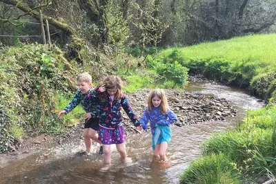 two children walking through a stream in the water at St. Tinney Farm in Bude