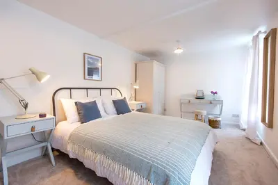 a white bedroom with a bed and a window at Cornish Cottage - Truro City Centre in Truro
