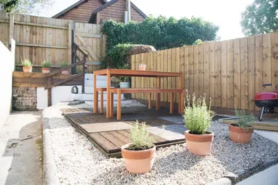 a garden with a wooden bench and potted plants at Cornish Cottage - Truro City Centre in Truro