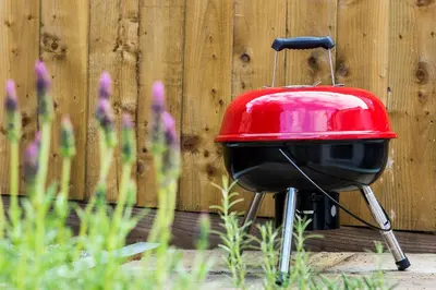 a red and black grill sitting in front of a fence at Cornish Cottage - Truro City Centre in Truro
