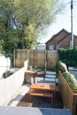 a patio with a wooden table and a wooden fence at Cornish Cottage - Truro City Centre in Truro