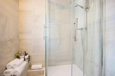 a shower with a glass door in a bathroom at Cornish Cottage - Truro City Centre in Truro