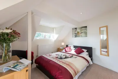 a bedroom with a bed with a vase of flowers on it at Rosemorran Holiday Apartments in St Ives