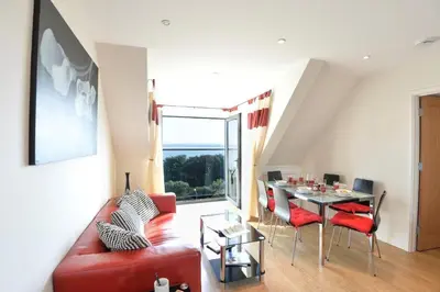 a living room with a red couch and a table at Rosemorran Holiday Apartments in St Ives