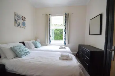 a bedroom with a large bed with a window at Rosemorran Holiday Apartments in St Ives