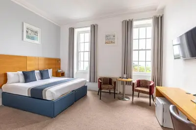 a hotel room with a bed and a table and chairs at Tregenna Castle Resort in St Ives
