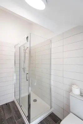 a white bathroom with a shower and a toilet at Tregenna Castle Resort in St Ives