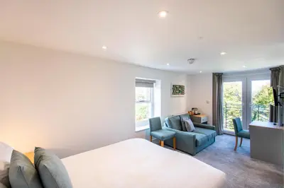 a bedroom with a bed and a couch and chairs at Tregenna Castle Resort in St Ives